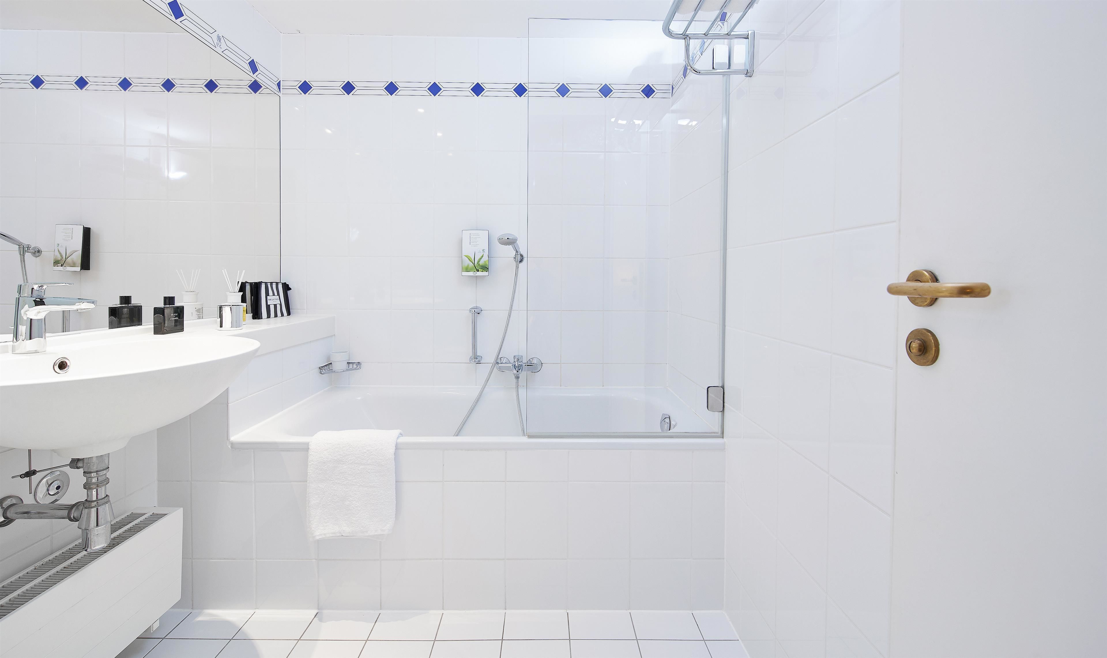 Un baño moderno con lavamanos blanco, espejo y zona de ducha.