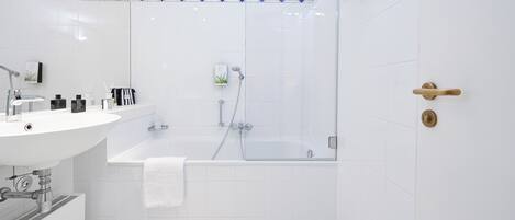 Un baño moderno con lavamanos blanco, espejo y zona de ducha.