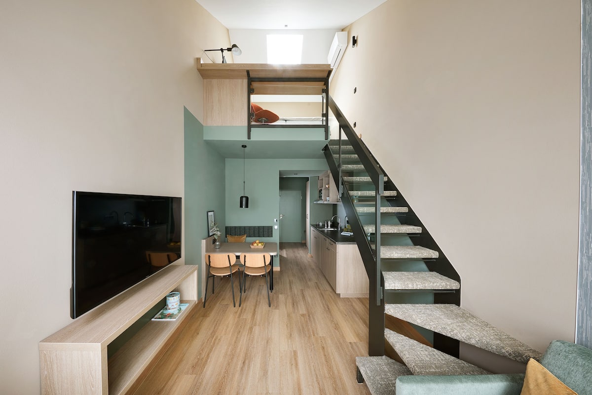 Ein modernes Interieur mit Essbereich, Küche und einer Treppe.
