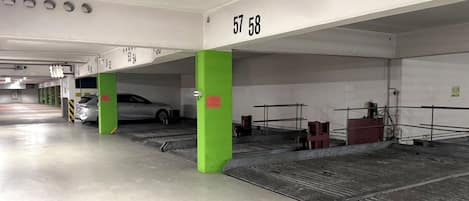 A parking garage with numbered parking spaces, a car parked in space 57, and a green pillar.