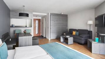 Una habitación de hotel moderna con cama, sofá, zona de comedor y televisión.
