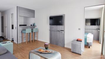 Un espacio habitable moderno y compacto con kitchenette, comedor y dormitorio.