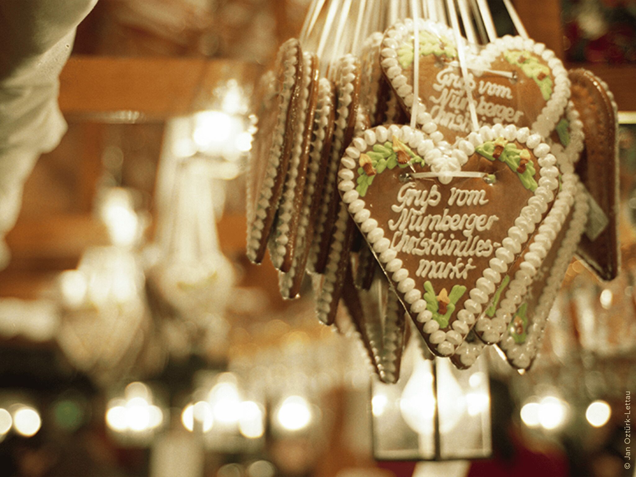 Heart-shaped gingerbread cookies with white icing decorations and text, displayed in a store.