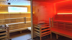 Uma sala de sauna com bancos de madeira e divisória de vidro.