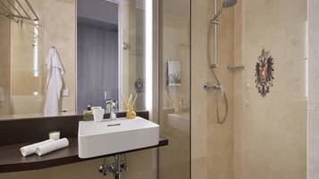 A modern bathroom with a glass shower enclosure, a white sink, and a large mirror.