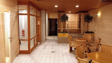 A hotel lobby with a tiled floor, wooden walls, a reception desk, and wicker furniture.