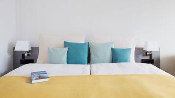 A neatly made bed with a yellow blanket, a book, and multiple pillows in shades of blue and white.