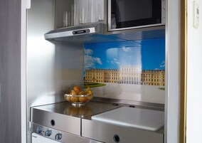 Cozinha com fogão de aço inoxidável, uma tigela de frutas e um mural decorativo de um edifício.