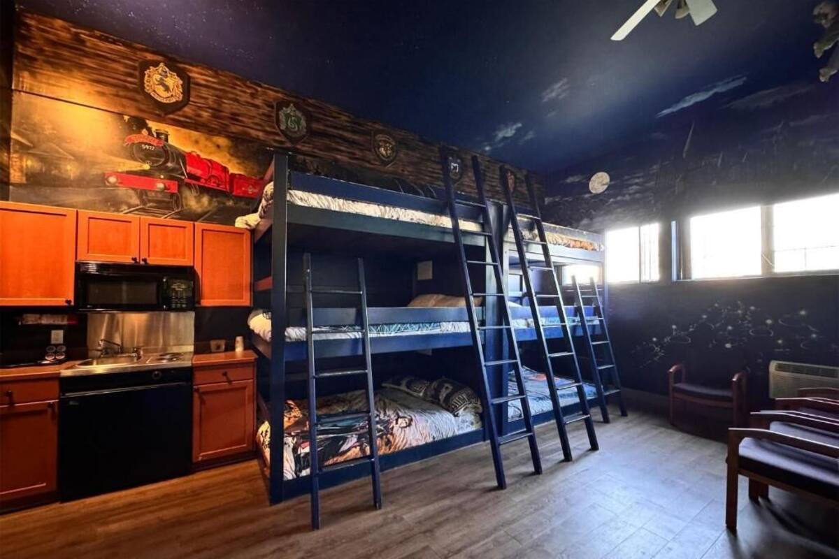 A bunk bed with a ladder, wooden cabinets, a kitchen area, and a mural on the wall.
