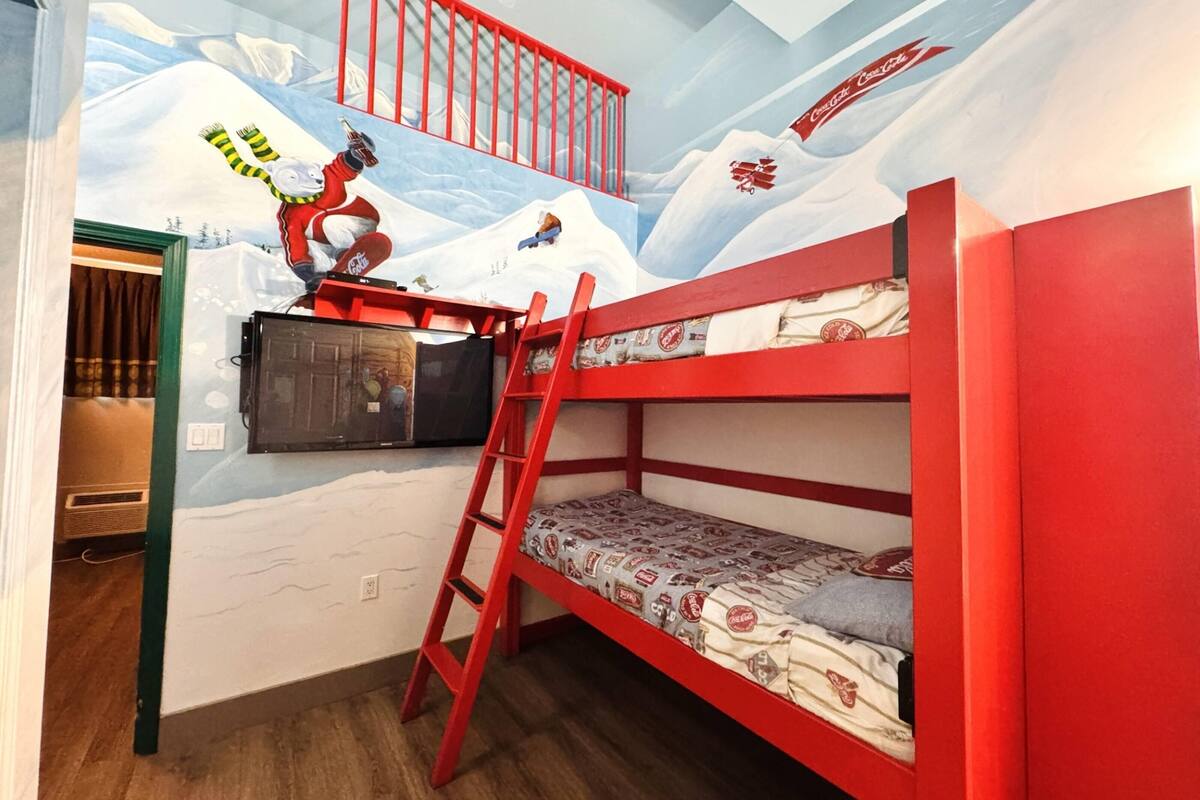 A child's room with bunk beds, a mural of a snowy mountain, and a ladder.
