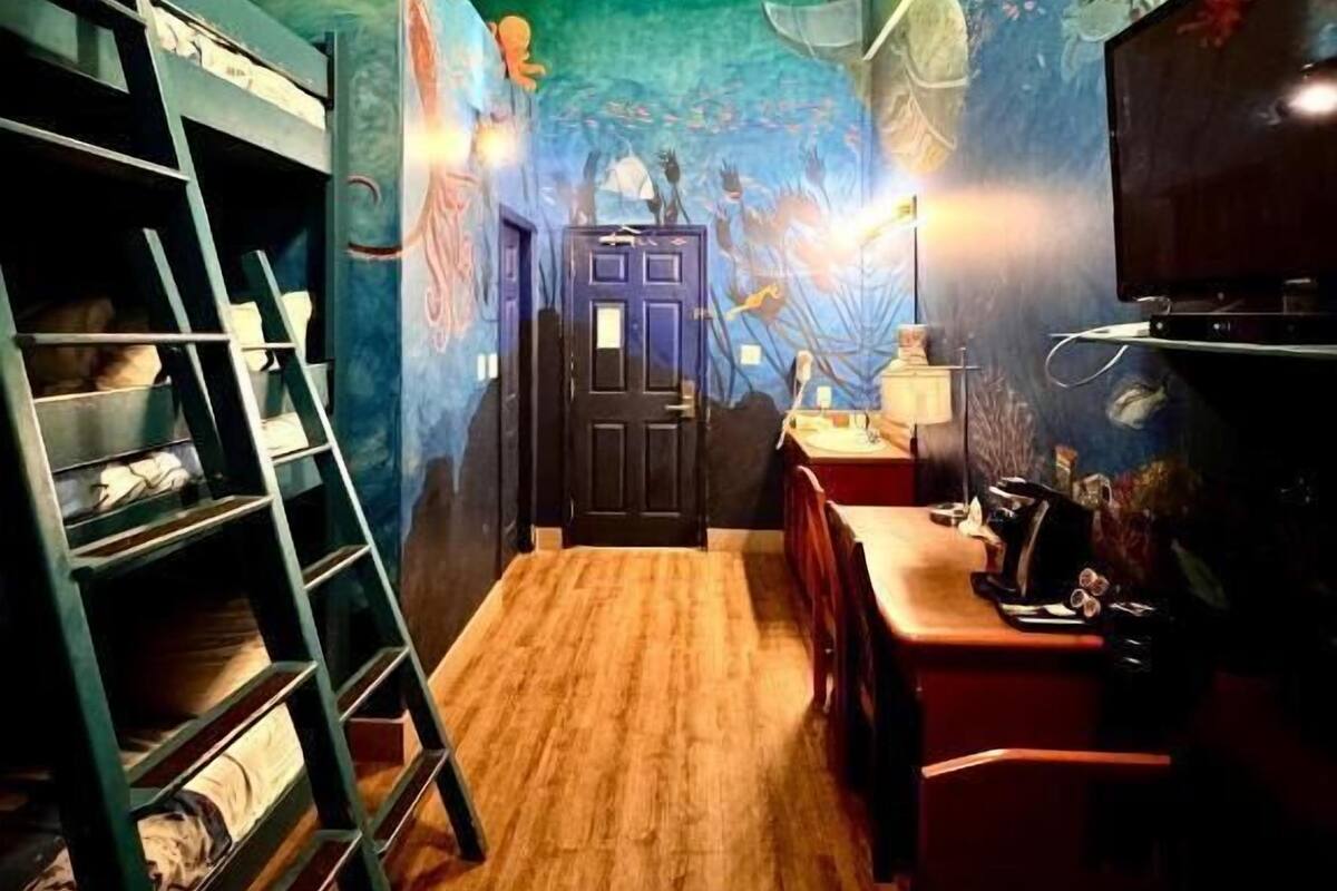 A room with bunk beds, a desk, and a door.