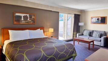 A hotel room with a large bed, a sofa, a coffee table, and a window with curtains.