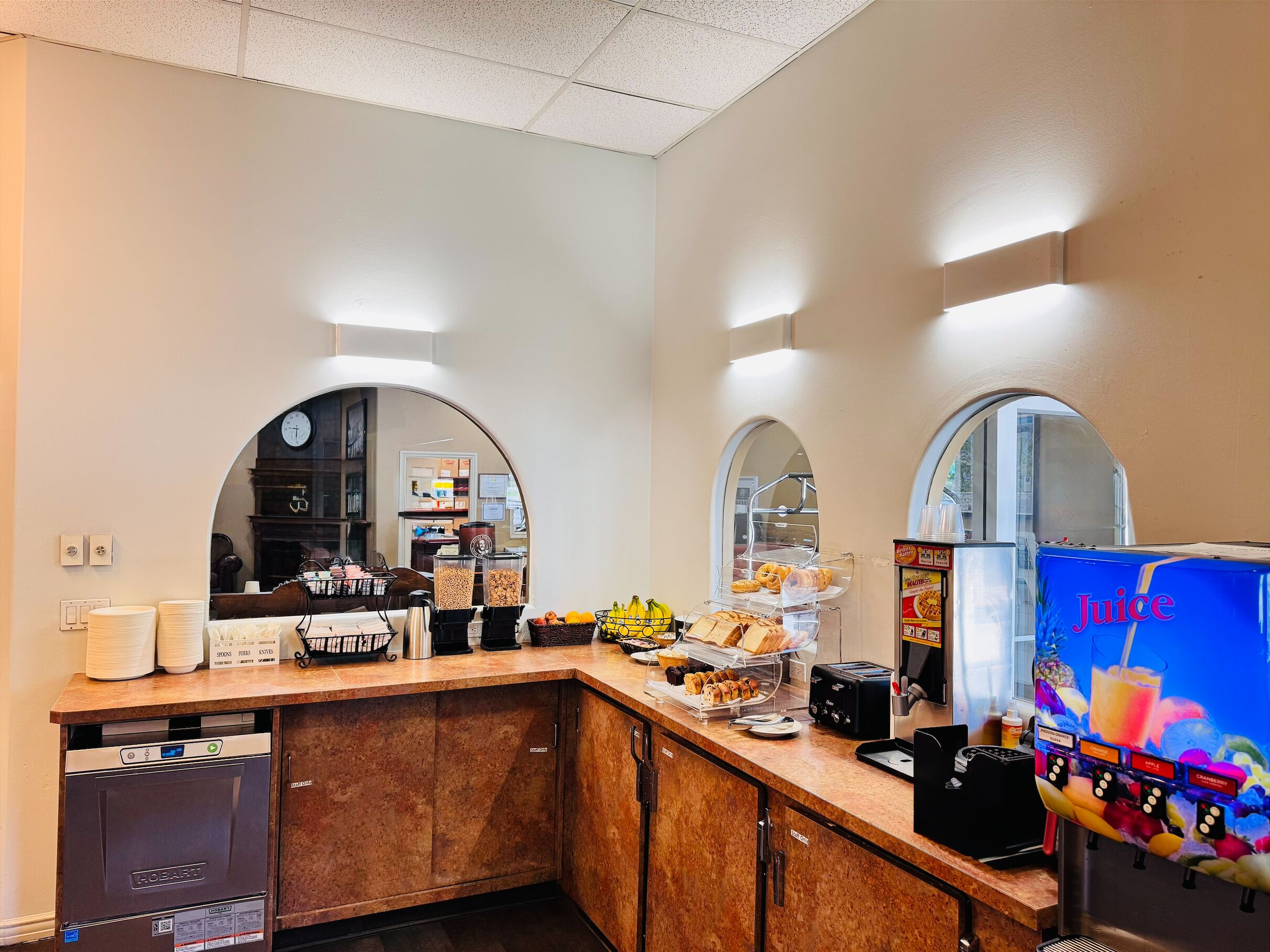A kitchen area with a coffee machine, a juice dispenser, and various food items on display.