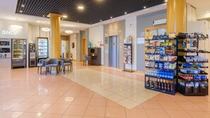 A clean, well-lit indoor area with vending machines, seating, and a shop sign. - B&B Hotel Ravenna (Ravenna)