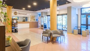 A hotel lobby with a reception desk, seating area, and a large pillar. - B&B Hotel Ravenna (Ravenna)