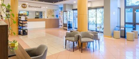 A hotel lobby with a reception desk, seating area, and a large pillar.
