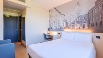 Ein Hotelzimmer mit Bett, Schreibtisch und Stuhl. Eine große Wandmalerei zeigt eine Stadtansicht.