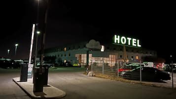 A hotel with a prominent 'HOTEL' sign, a parking lot, and a gated entrance.