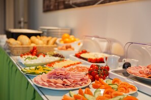 Una mesa de buffet con diversos alimentos, incluyendo carnes, quesos y verduras.