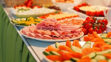 Una mesa de buffet con diversos alimentos, incluyendo carnes, quesos y verduras.