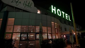 A hotel with a large sign reading "Life Hotel" and "HOTEL" in bright green lights. - Life Hotel (Fischamend)