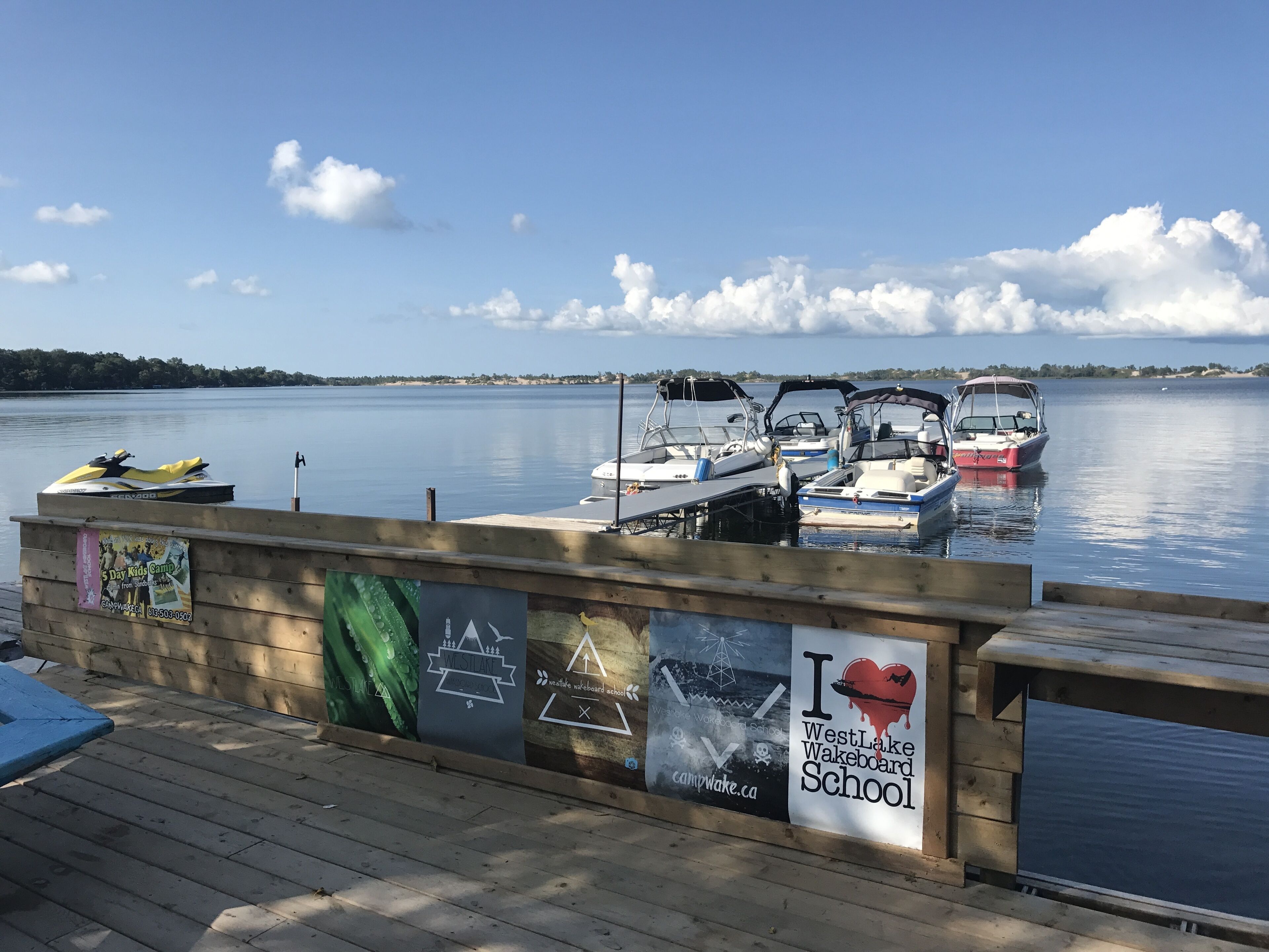 Un muelle de madera con un cartel de WestLake Wakeboard School.