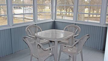 A corner room with a round table and four chairs, large windows, and a view of the outdoors.