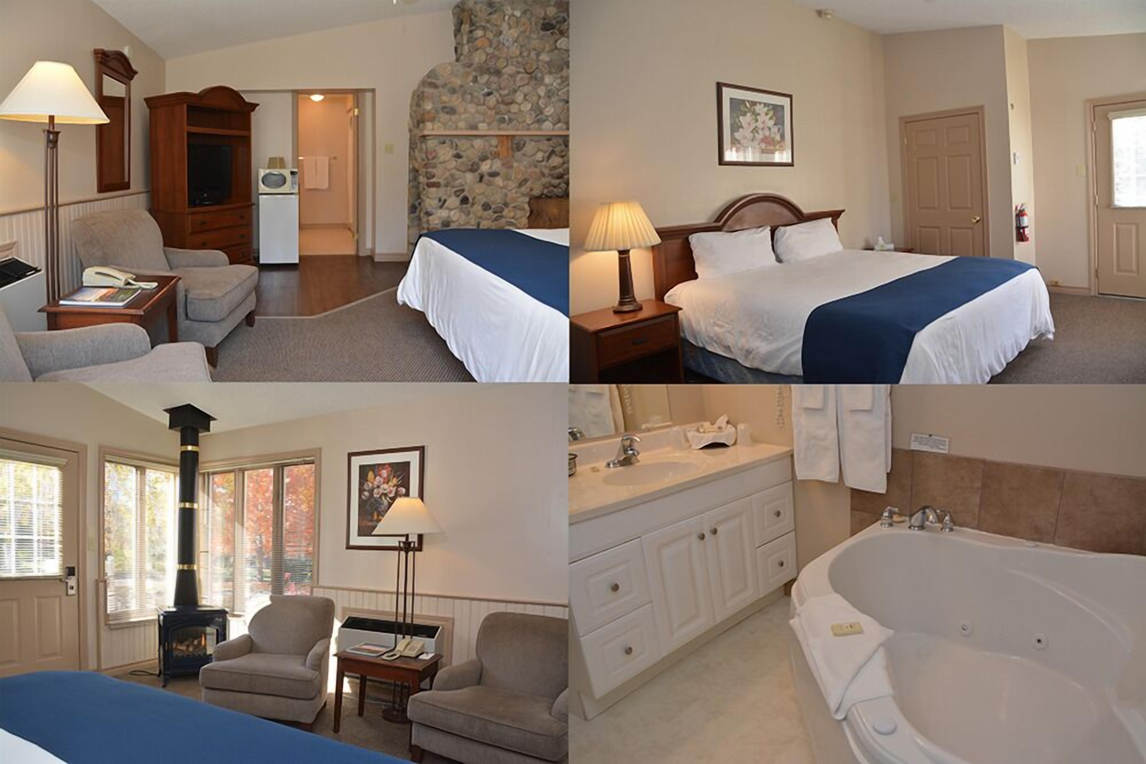 Una habitación de hotel con cama, zona de estar con una silla y una mesa, kitchenette, baño con bañera y pared de piedra.