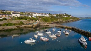 A harbor with various boats docked, a stone quay, and houses in the background. - Bayview Hotel (Ballycotton)