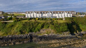 A coastal hotel with multiple-story buildings, a rocky shoreline, and a well-maintained garden. - Bayview Hotel (Ballycotton)