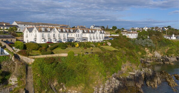 A coastal residential area with a prominent white building featuring multiple gabled roofs and a large garden. - Bayview Hotel (Ballycotton)
