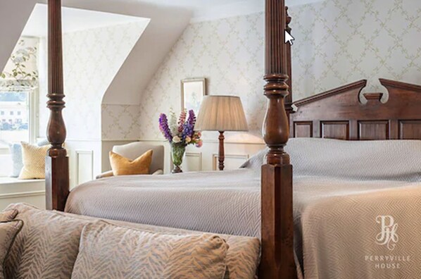 Una cama con dosel, un cabecero de madera, un florero con flores y una lámpara en una mesita de noche.