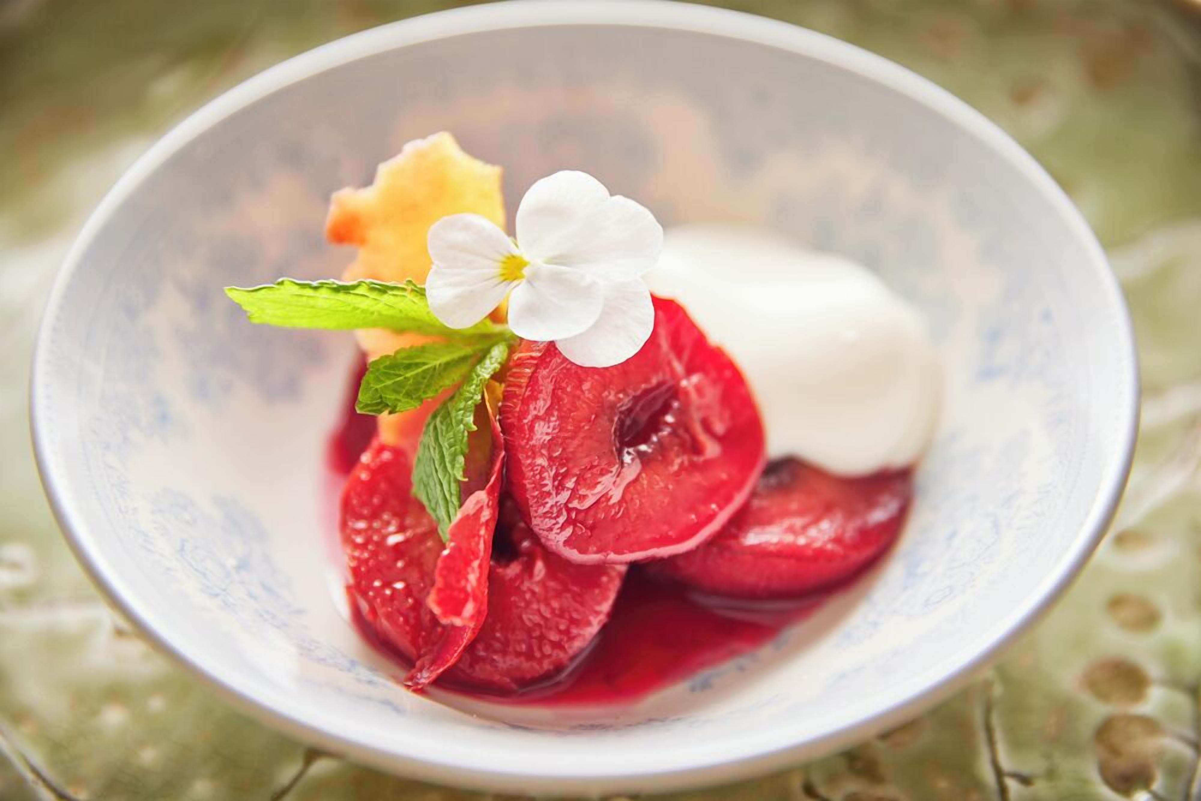 Un tazón de postre con frutas en rodajas y una flor blanca como adorno.