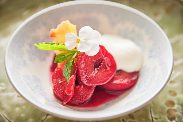A bowl of dessert with sliced fruits and a white flower garnish.