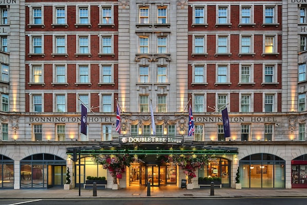 Un hotel con fachada simétrica, múltiples ventanas y una entrada central con toldo.