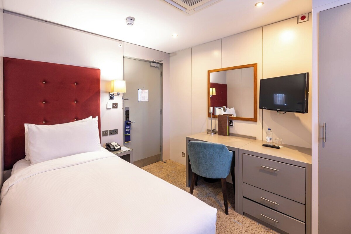Une chambre d’hôtel comprenant un lit, un bureau, une chaise, une télévision et un miroir.
