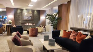 A modern lounge area with sofas, armchairs, a coffee table, and a fireplace. - DoubleTree by Hilton London West End (London)