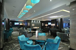 Relax in the hotel lobby's central seating area, featuring a fireplace and flat-screen TV.