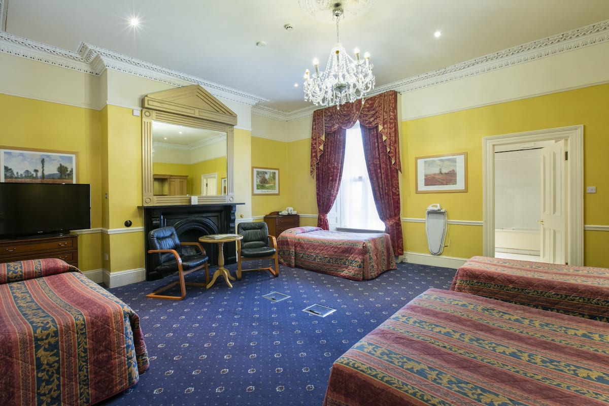 Habitación de hotel con dos camas, televisión, chimenea y candelabro.