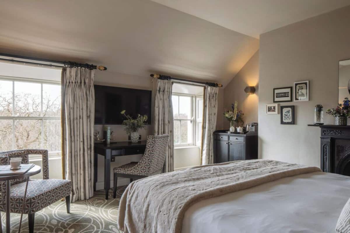 A bedroom with a bed, a desk, a chair, and a television.