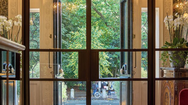 Una entrada imponente con puerta de cristal que da a un jardín exuberante.