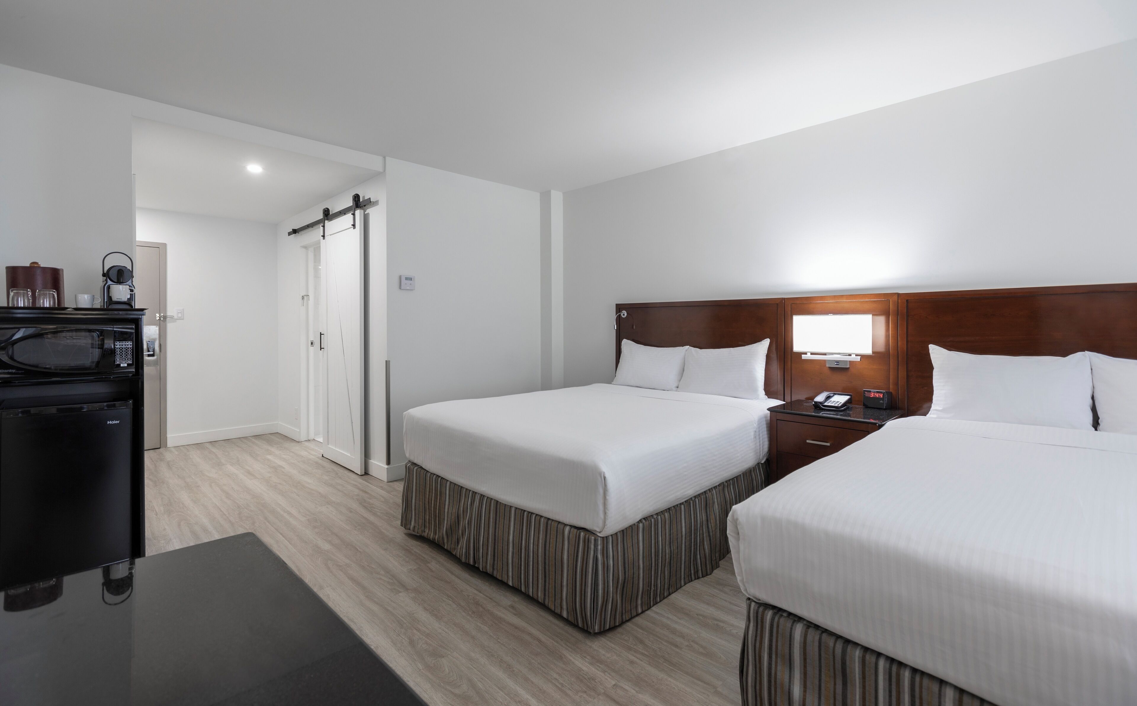 Una habitación de hotel con dos camas, un escritorio, un microondas, una cafetera y un televisor.