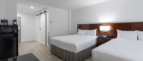 Una habitación de hotel con dos camas, un escritorio, un microondas, una cafetera y un televisor.