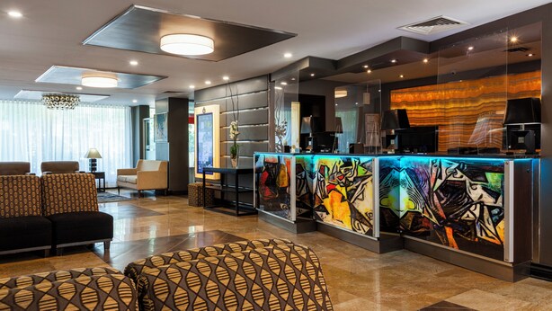 Un vestíbulo moderno con mostrador de recepción, zona de estar y obras de arte.