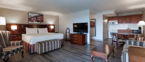 Una habitación de hotel con cama, televisión, mesa de comedor y zona de cocina.