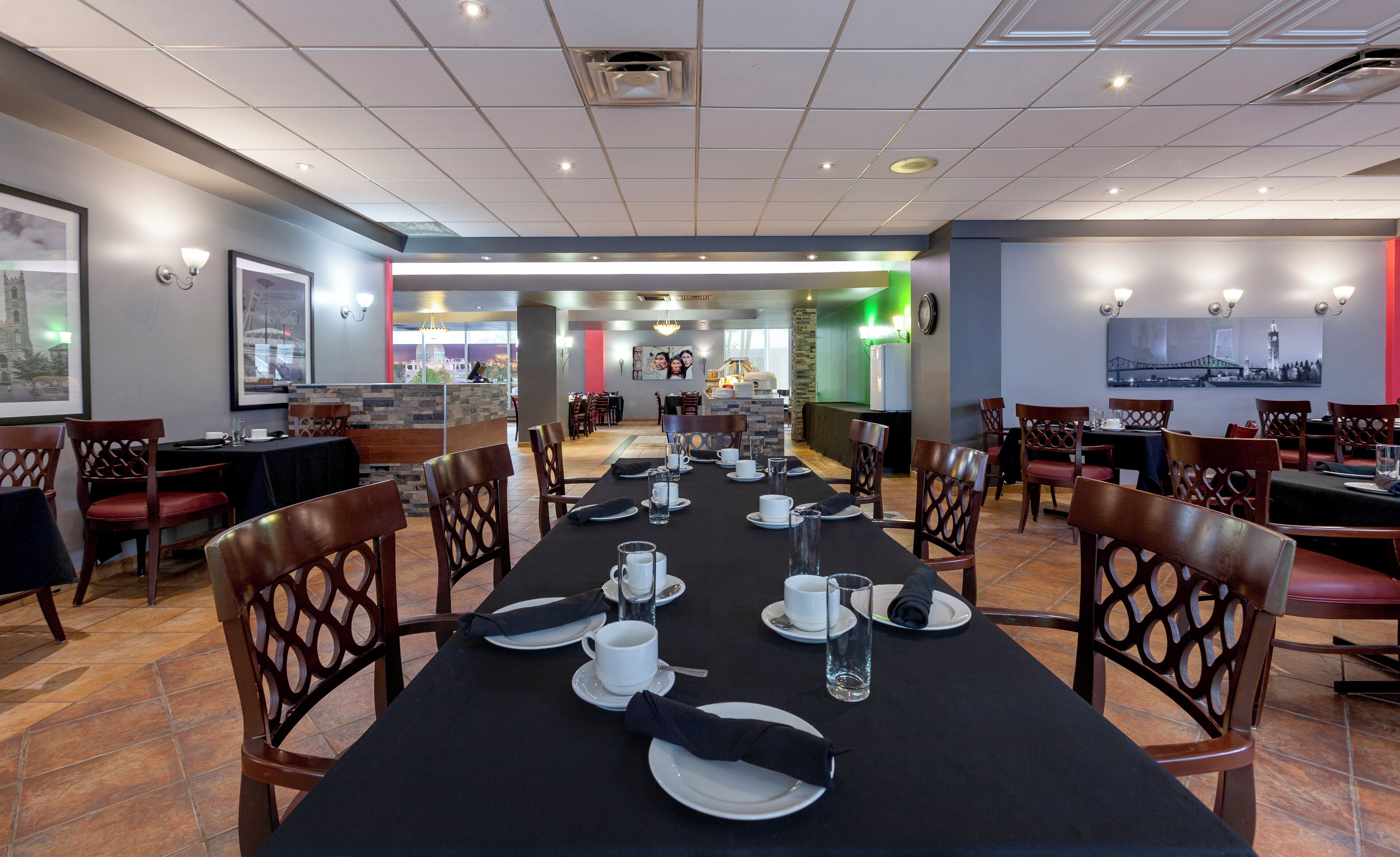A restaurant with a long table set for a meal, surrounded by wooden chairs.