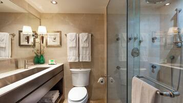 Un baño moderno con ducha de vidrio, tocador con espejo y retrete.