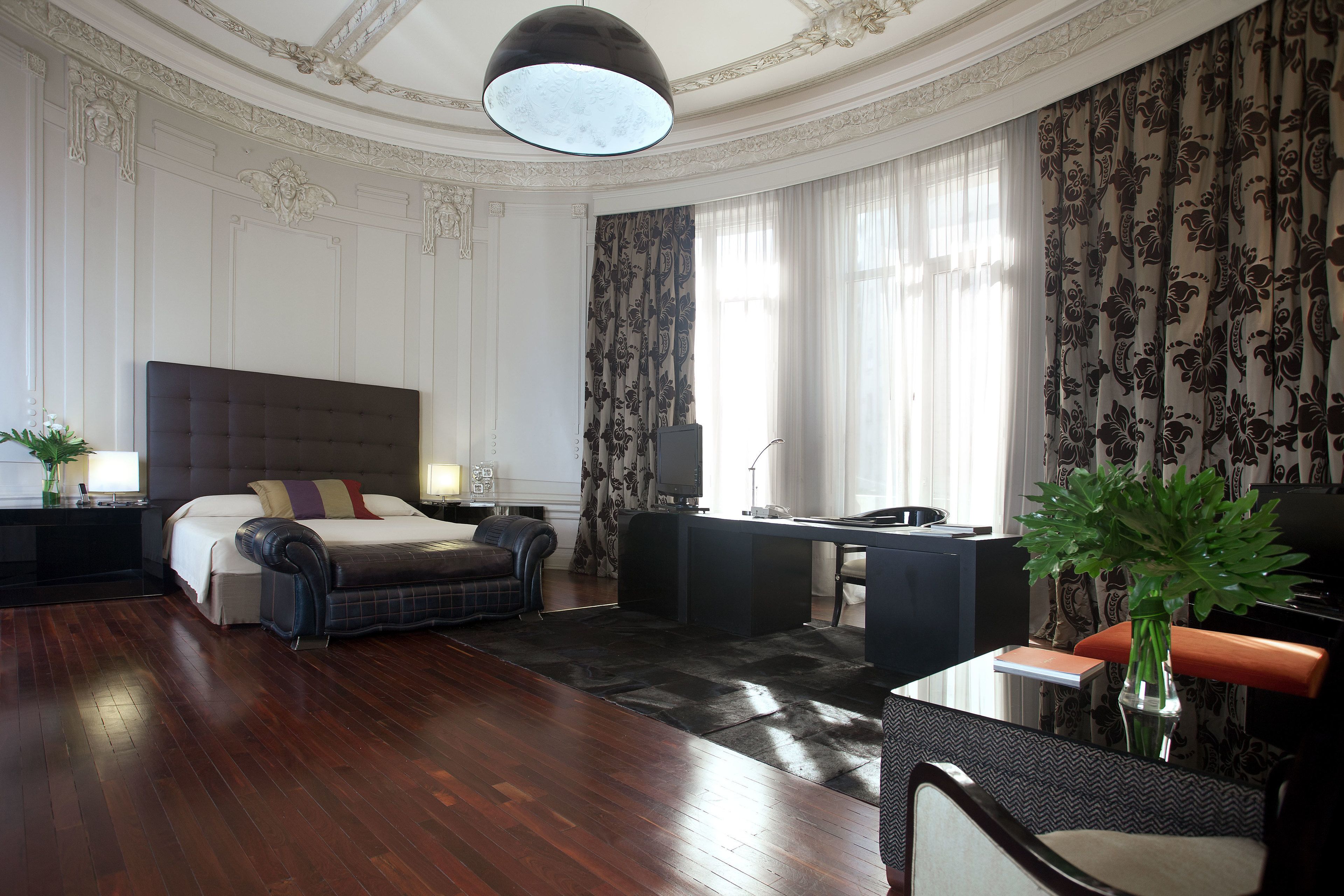 Habitación de hotel con una cama grande, un escritorio, una silla, un televisor y un florero con plantas.