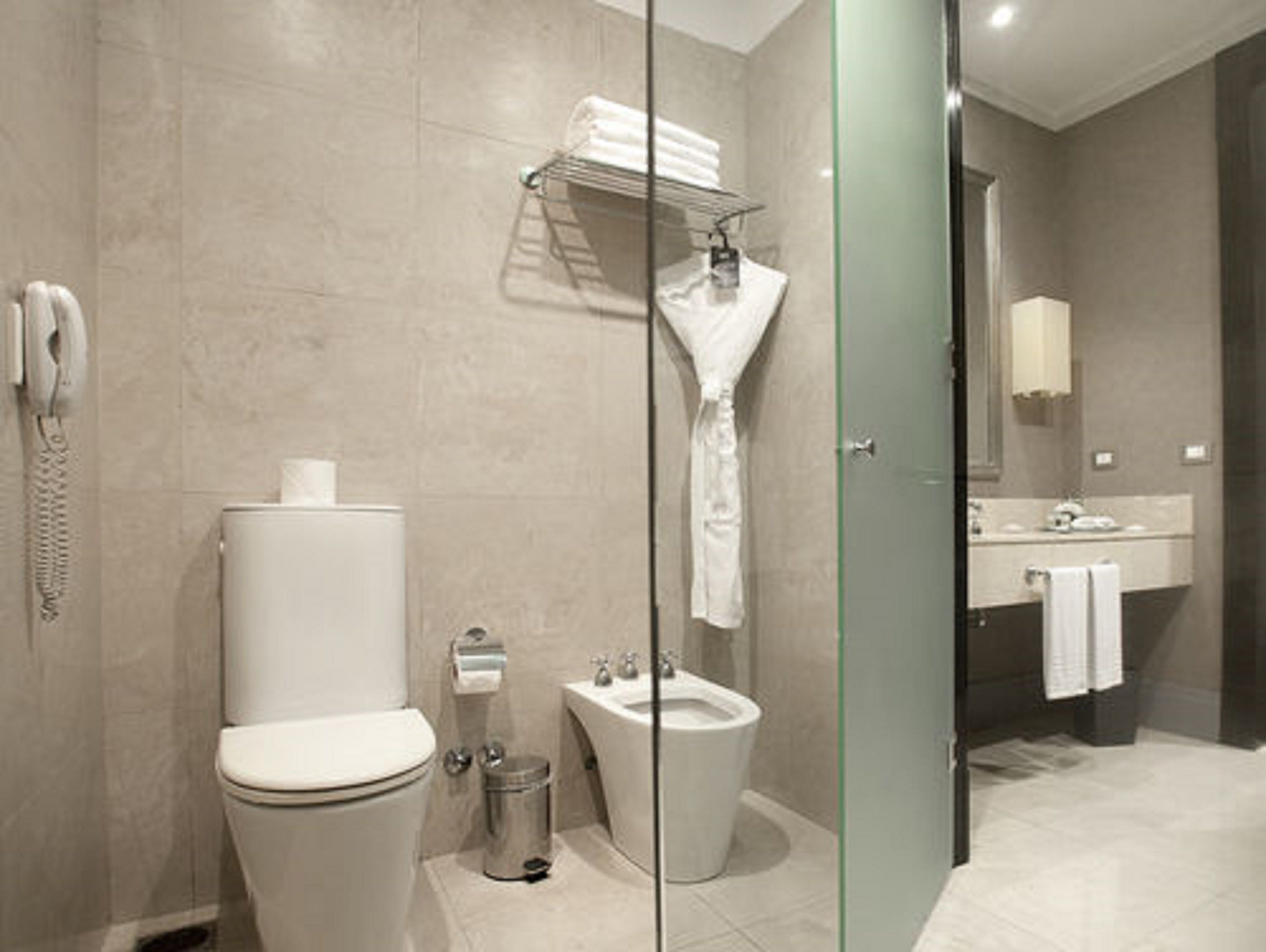 A modern bathroom with a toilet, bidet, and glass shower enclosure.