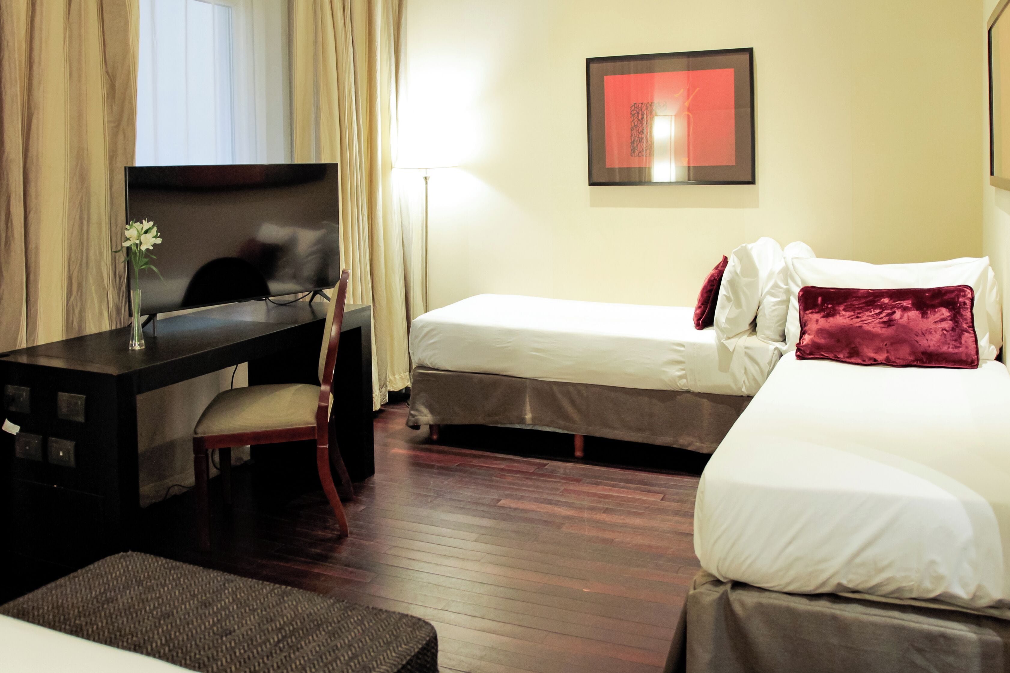 A hotel room with a bed, a desk, and a chair.